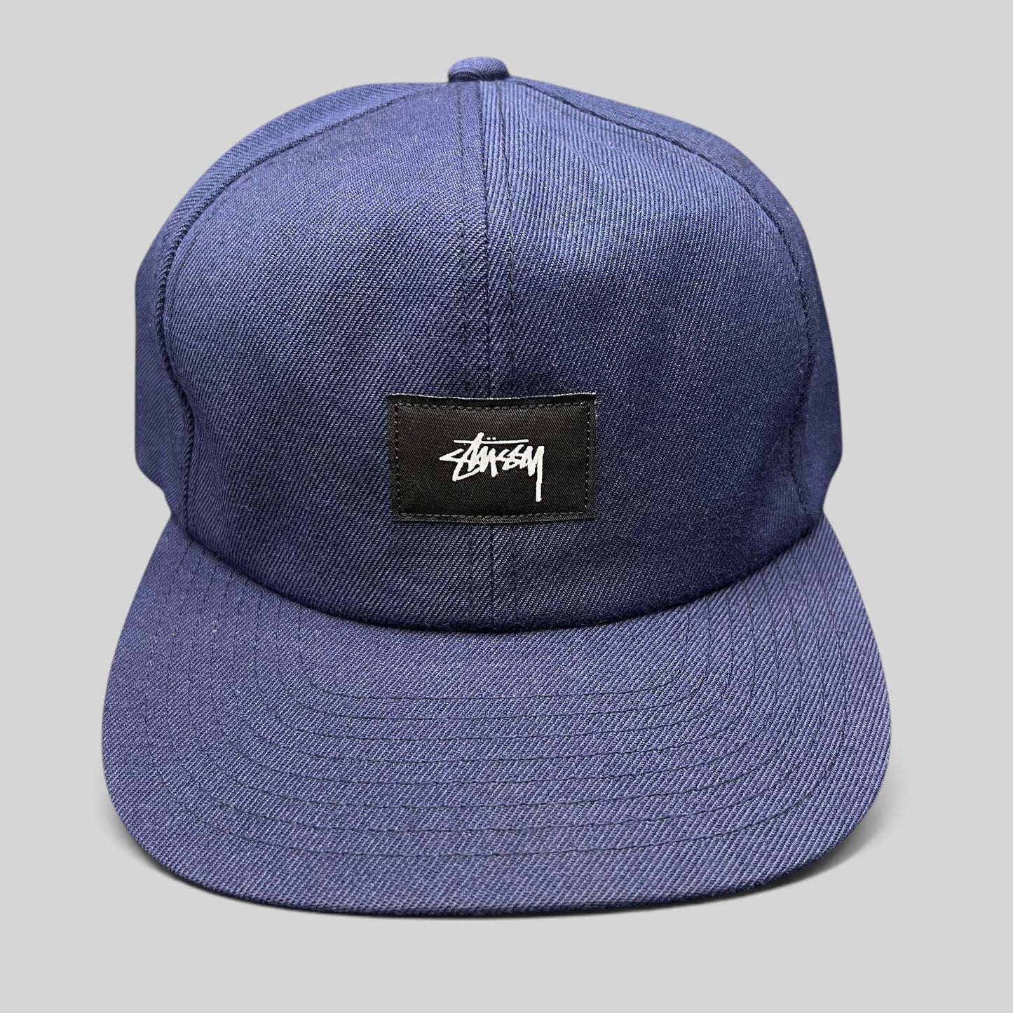 Raree Finds navy Stussy strapback hat featuring a minimalist black box logo patch with white signature script.
