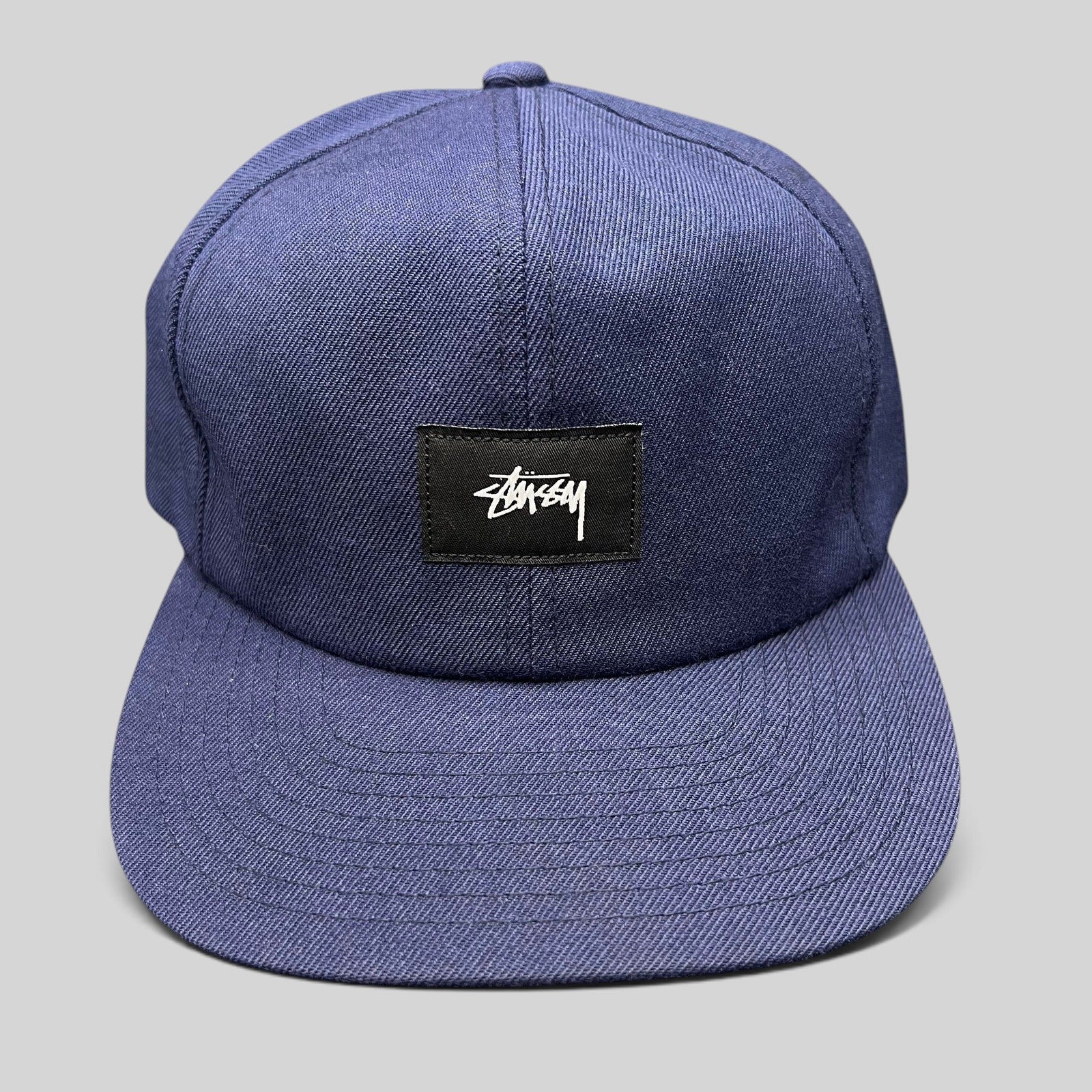 Raree Finds navy Stussy strapback hat featuring a minimalist black box logo patch with white signature script.