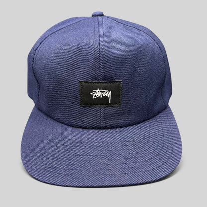 Raree Finds navy Stussy strapback hat featuring a minimalist black box logo patch with white signature script.