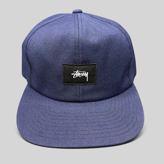 Raree Finds navy Stussy strapback hat featuring a minimalist black box logo patch with white signature script.