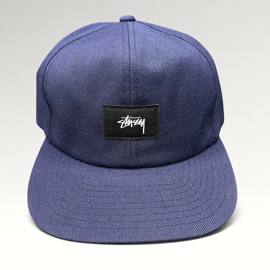 Raree Finds navy Stussy strapback hat featuring a minimalist black box logo patch with white signature script.