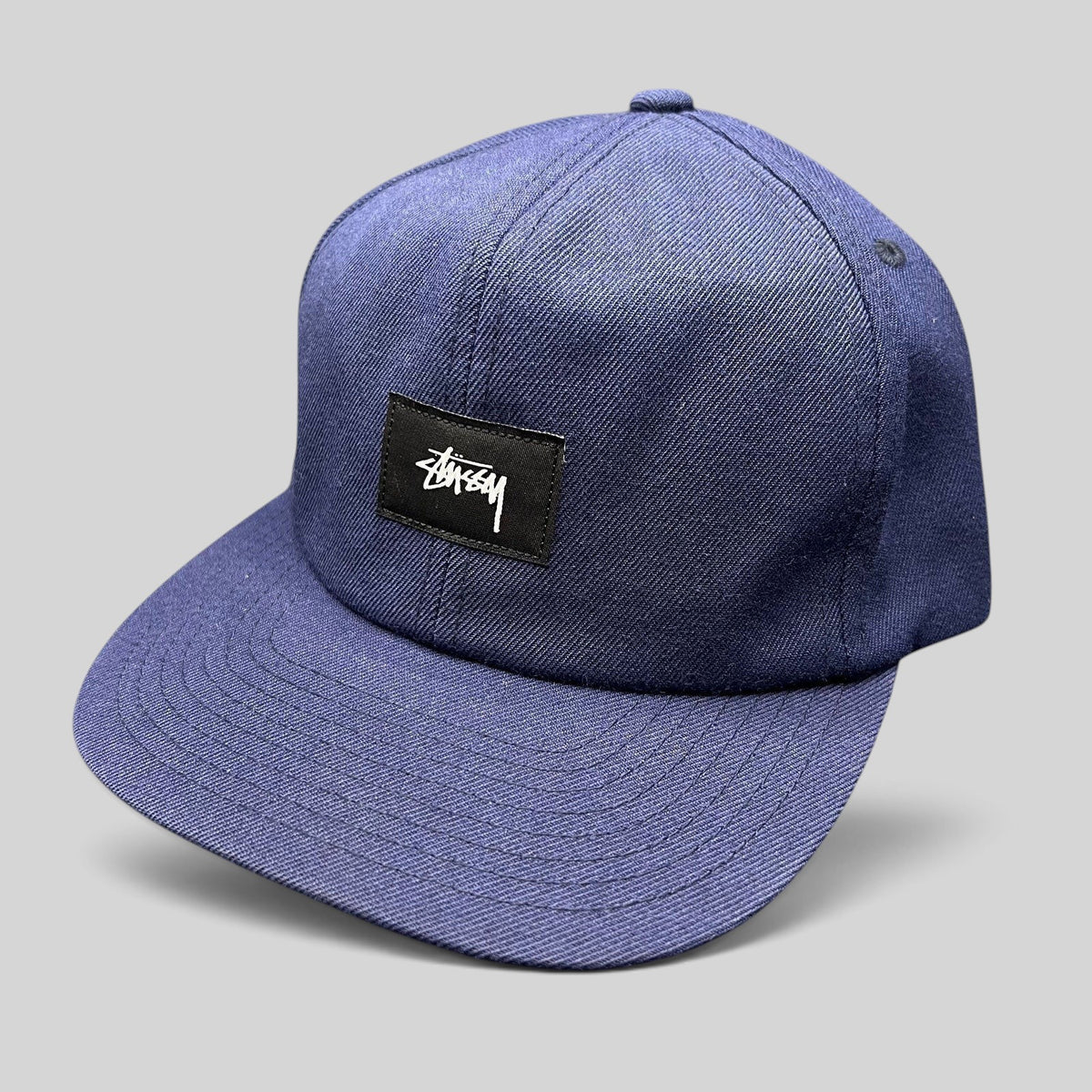 Raree Finds navy Stussy strapback hat with a minimalist black box logo patch and white script embroidery