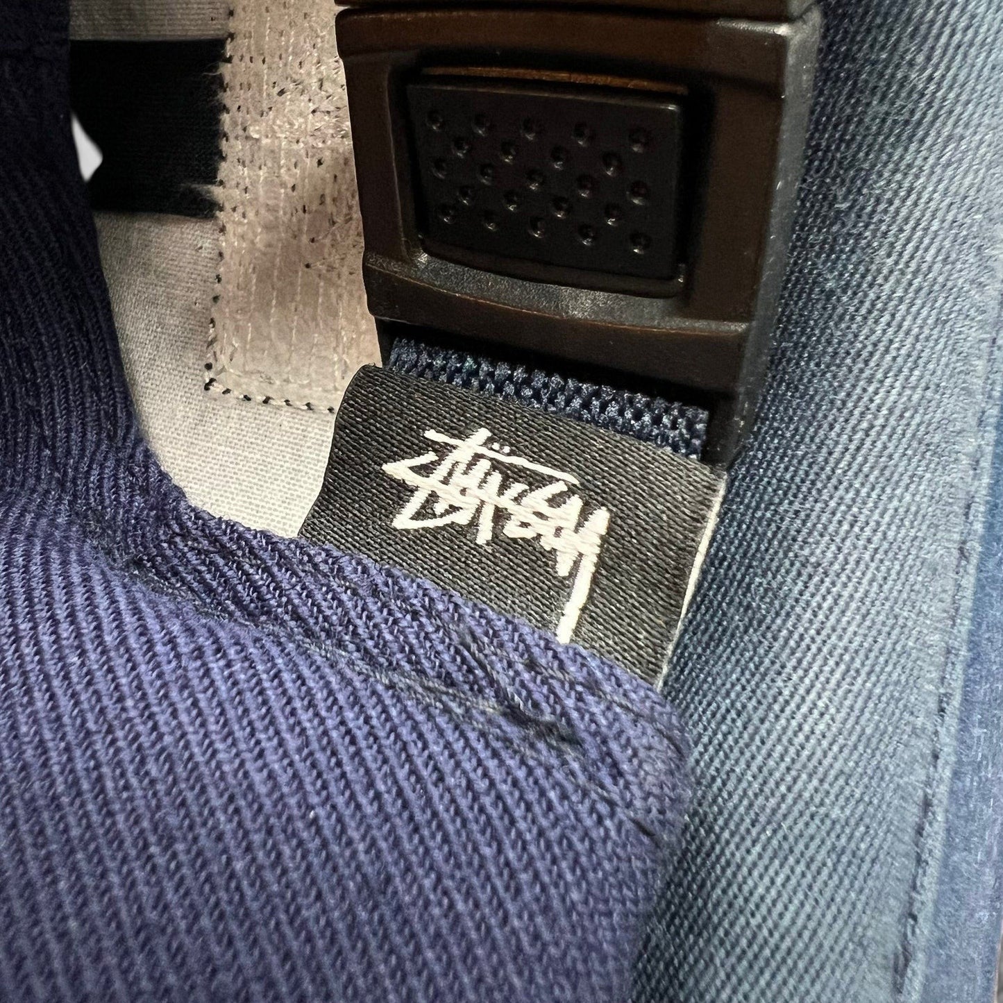 Raree Finds navy Stussy strapback hat featuring a black interior fabric tag with white signature script logo