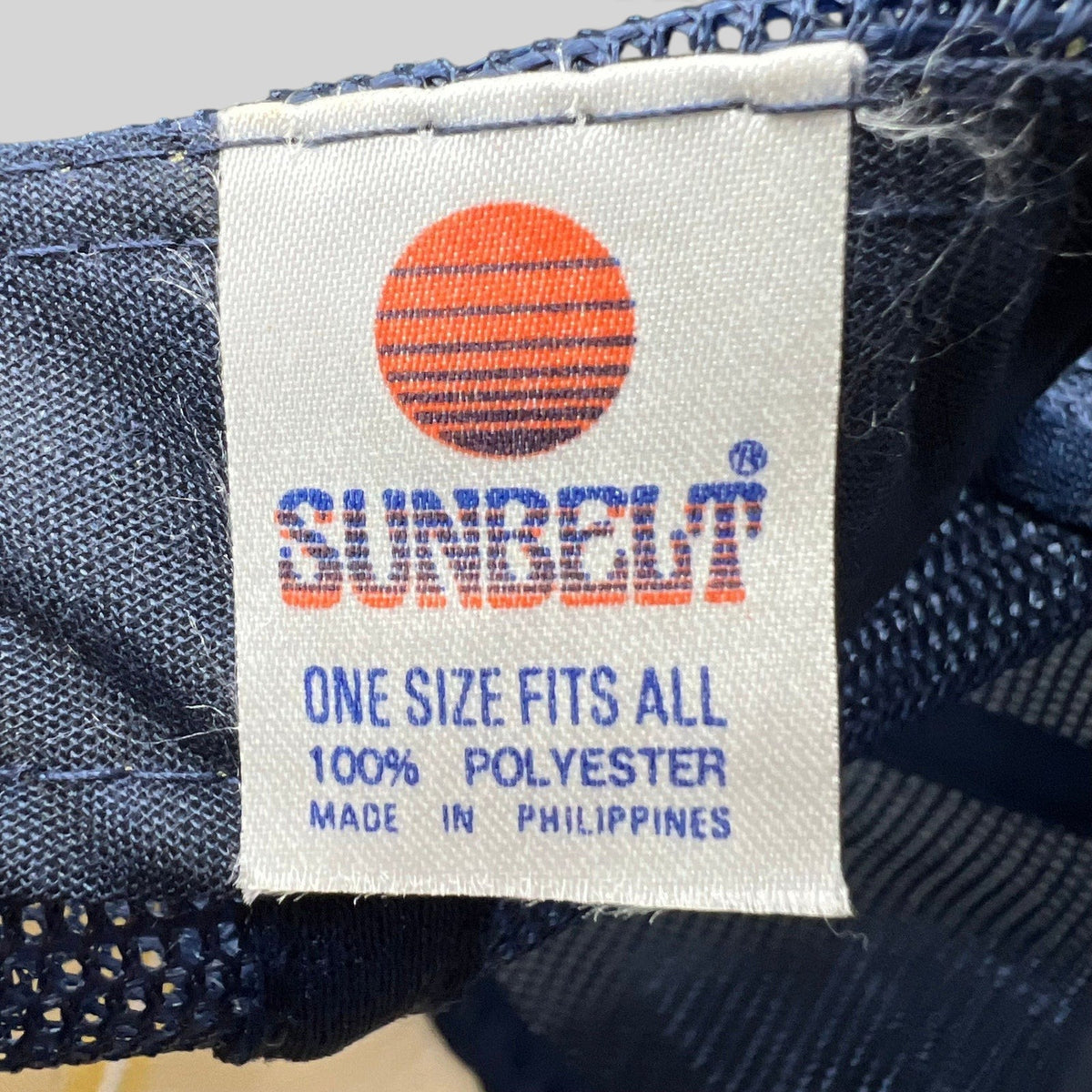 Raree Finds vintage Sunbelt trucker hat interior tag showing brand logo, material composition, and origin