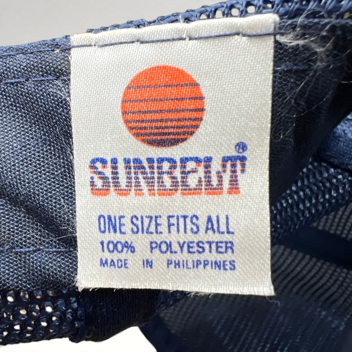 Raree Finds vintage Sunbelt trucker hat interior tag showing brand logo, material composition, and origin