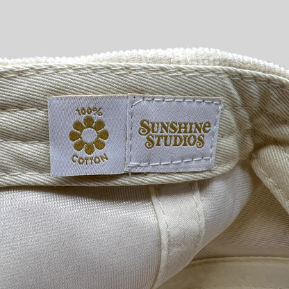 Raree Finds Sunshine Studios cream corduroy hat interior label with 100% cotton flower logo and brand text