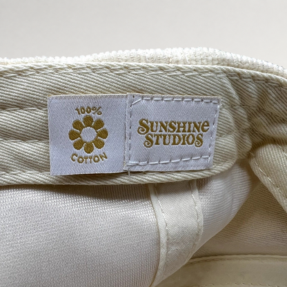 Raree Finds Sunshine Studios cream corduroy hat interior label with 100% cotton flower logo and brand text