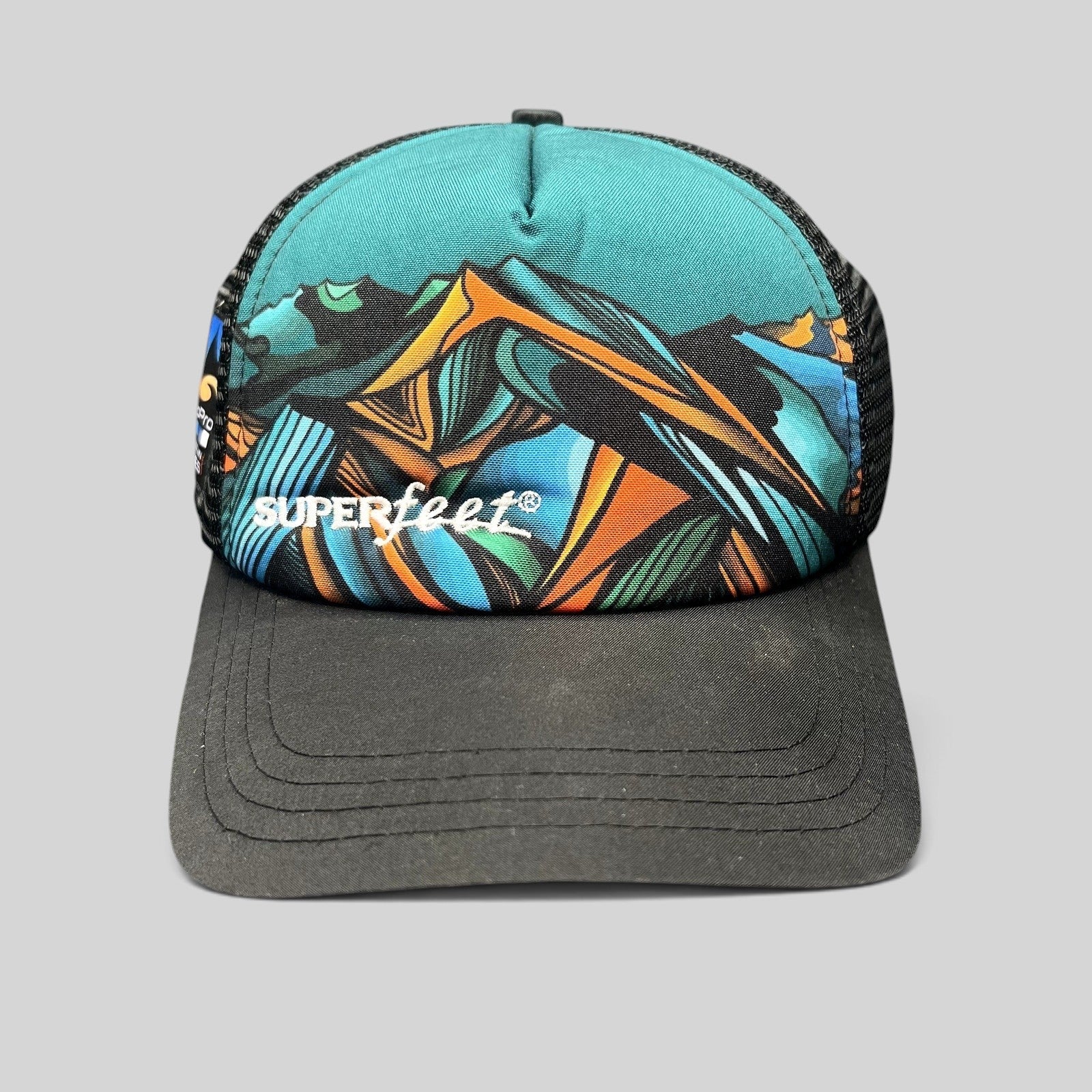Raree Finds Superfeet GoPro Mountain Games trucker hat with abstract mountain graphic, black mesh, and snapback closure.