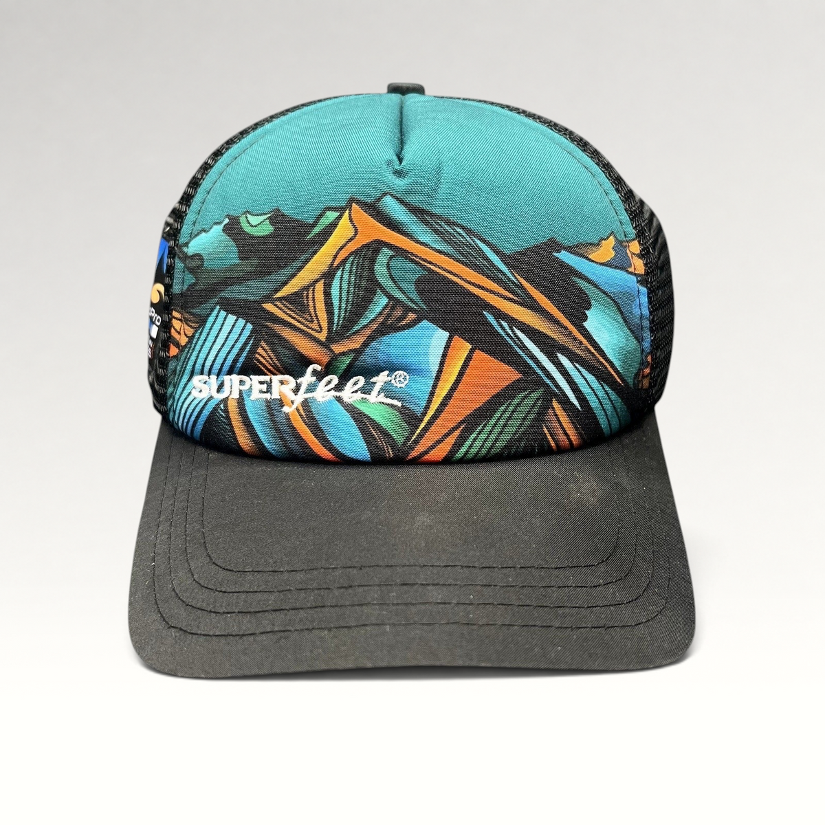 Raree Finds Superfeet GoPro Mountain Games trucker hat with abstract mountain graphic, black mesh, and snapback closure.