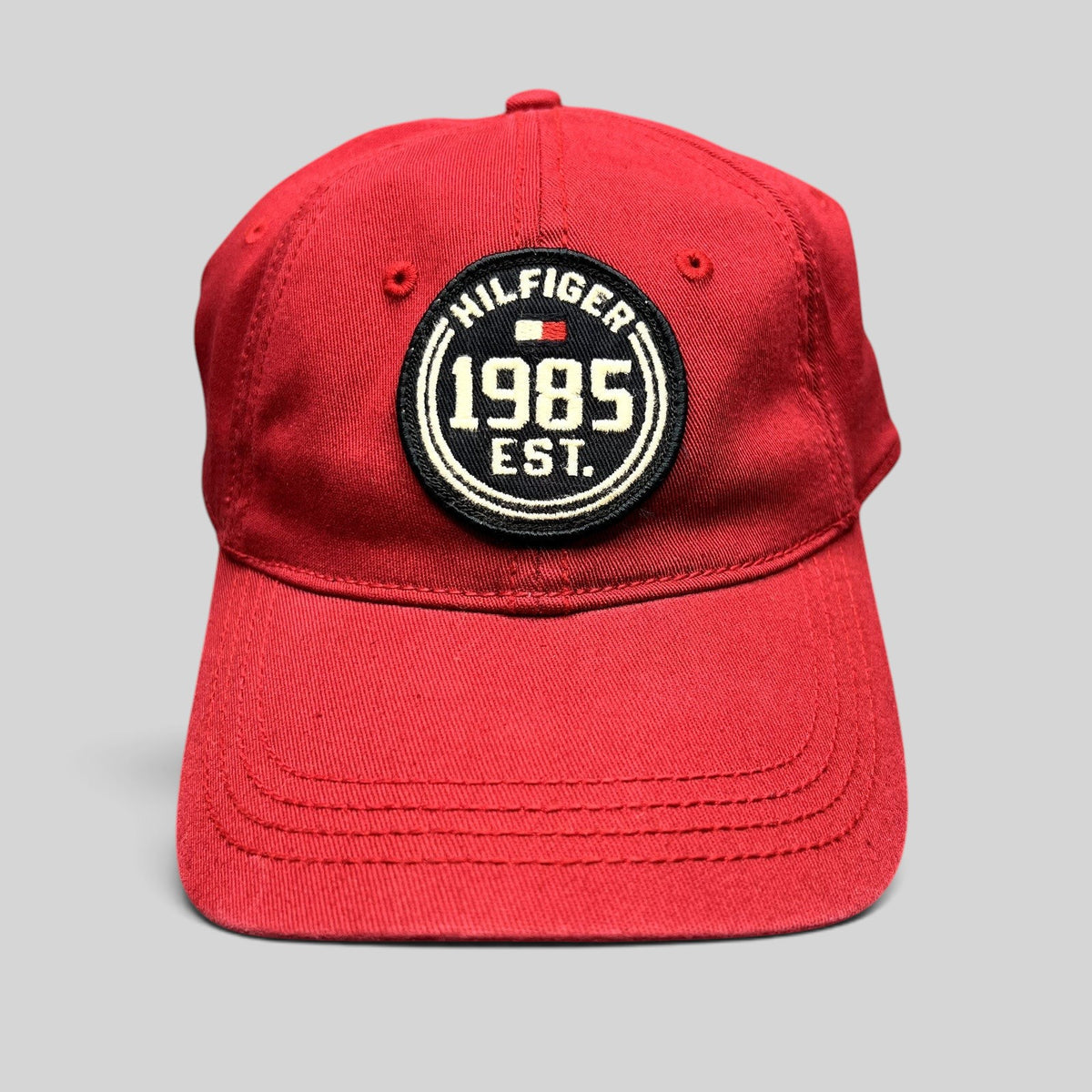 Raree Finds red Tommy Hilfiger 1985 EST fitted hat with a circular embroidered patch and curved brim.