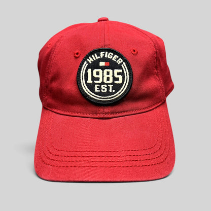Raree Finds red Tommy Hilfiger 1985 EST fitted hat with a circular embroidered patch and curved brim.