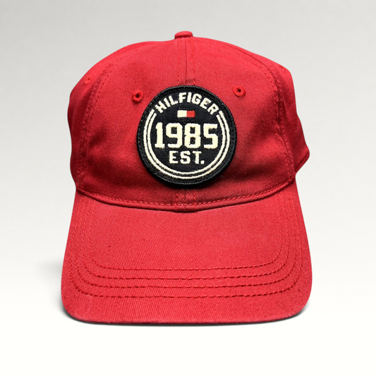 Raree Finds red Tommy Hilfiger 1985 EST fitted hat with a circular embroidered patch and curved brim.