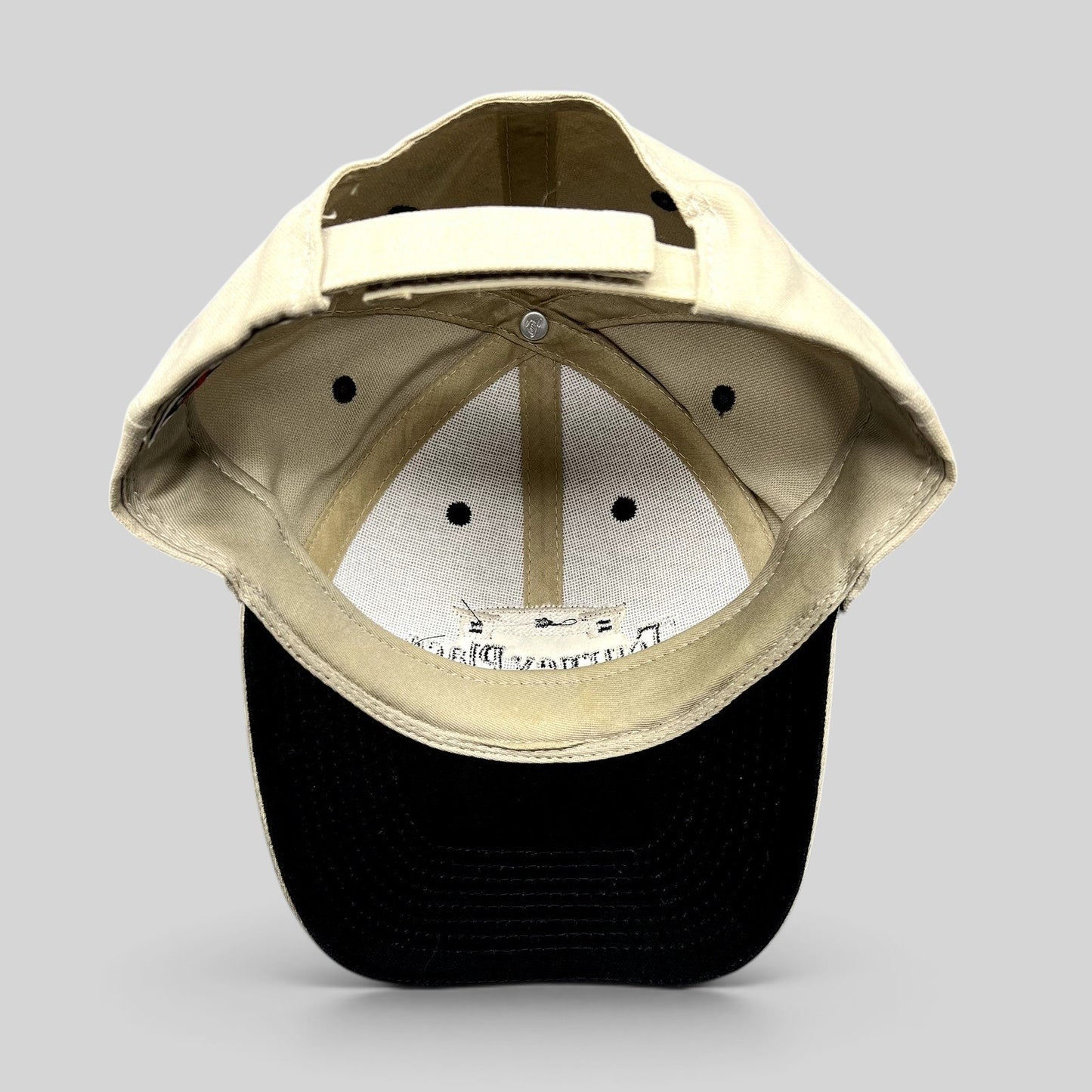 Raree Finds Tourney Place dad hat showing the interior khaki crown, black brim, and adjustable strapback closure.