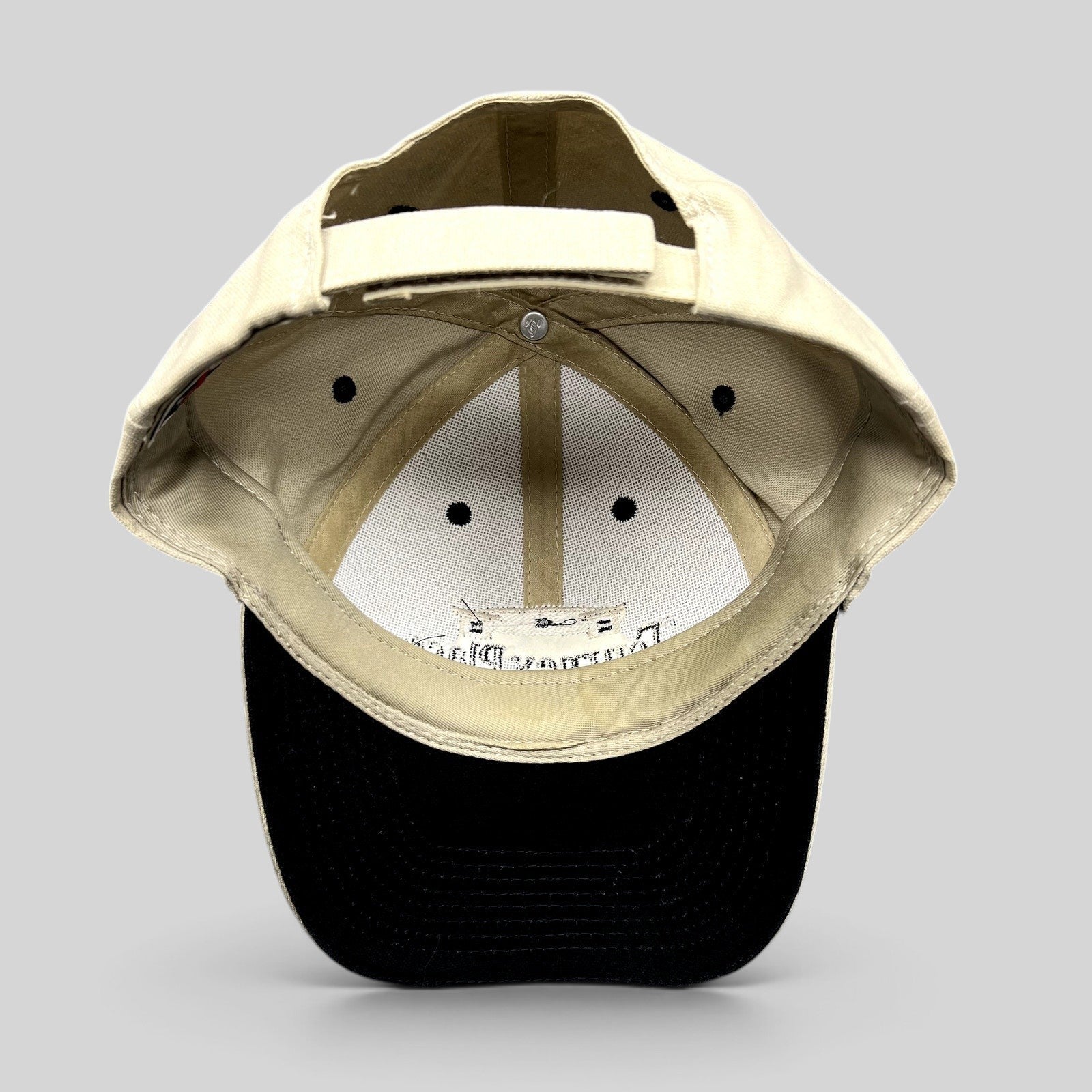 Raree Finds Tourney Place dad hat showing the interior khaki crown, black brim, and adjustable strapback closure.