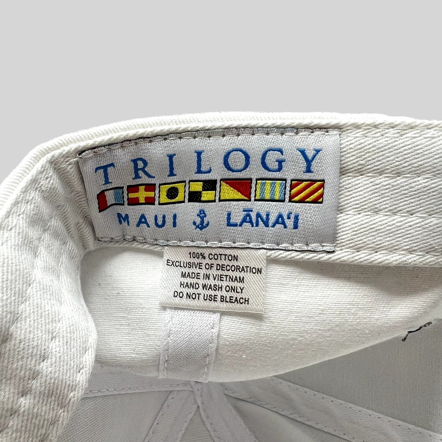 Raree Finds white cotton cap interior label featuring Trilogy Maui Lana‘i branding and nautical signal flags