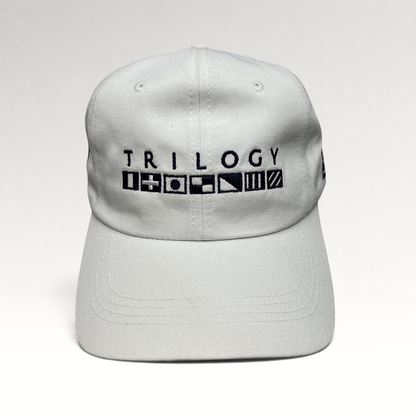 Raree Finds white cotton strapback cap featuring Trilogy branding and embroidered nautical signal flags on the front.