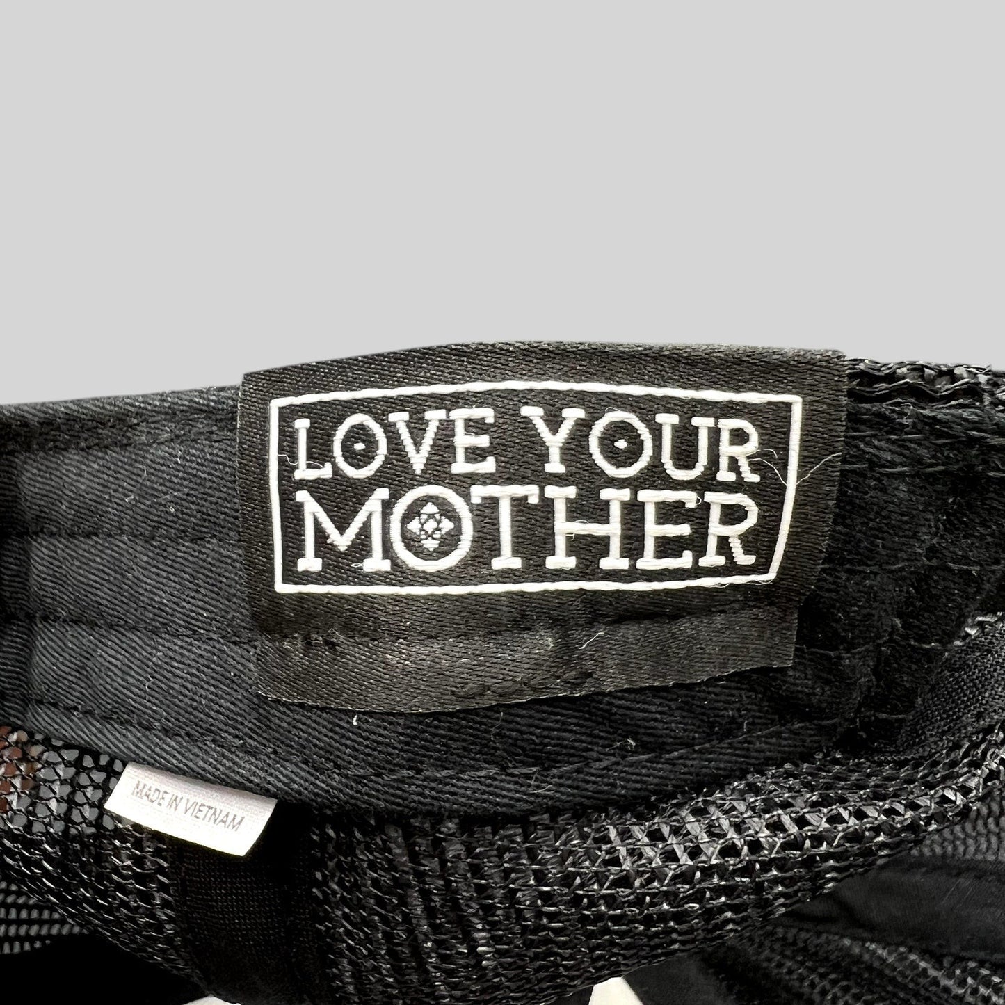 Raree Finds black trucker hat interior tag reading Love Your Mother with a Made in Vietnam label