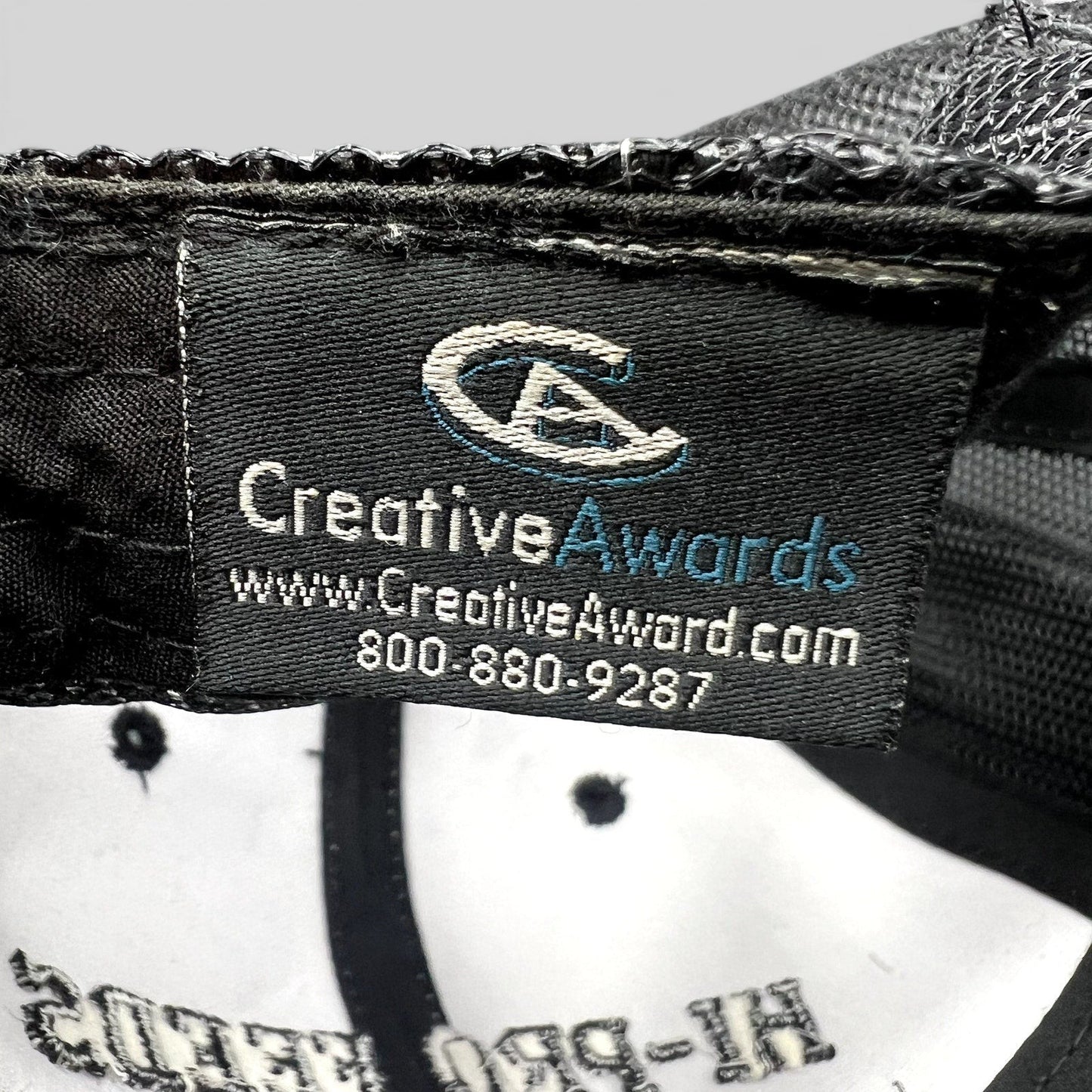 Raree Finds branded trucker hat interior tag showing Creative Awards manufacturer logo and contact information