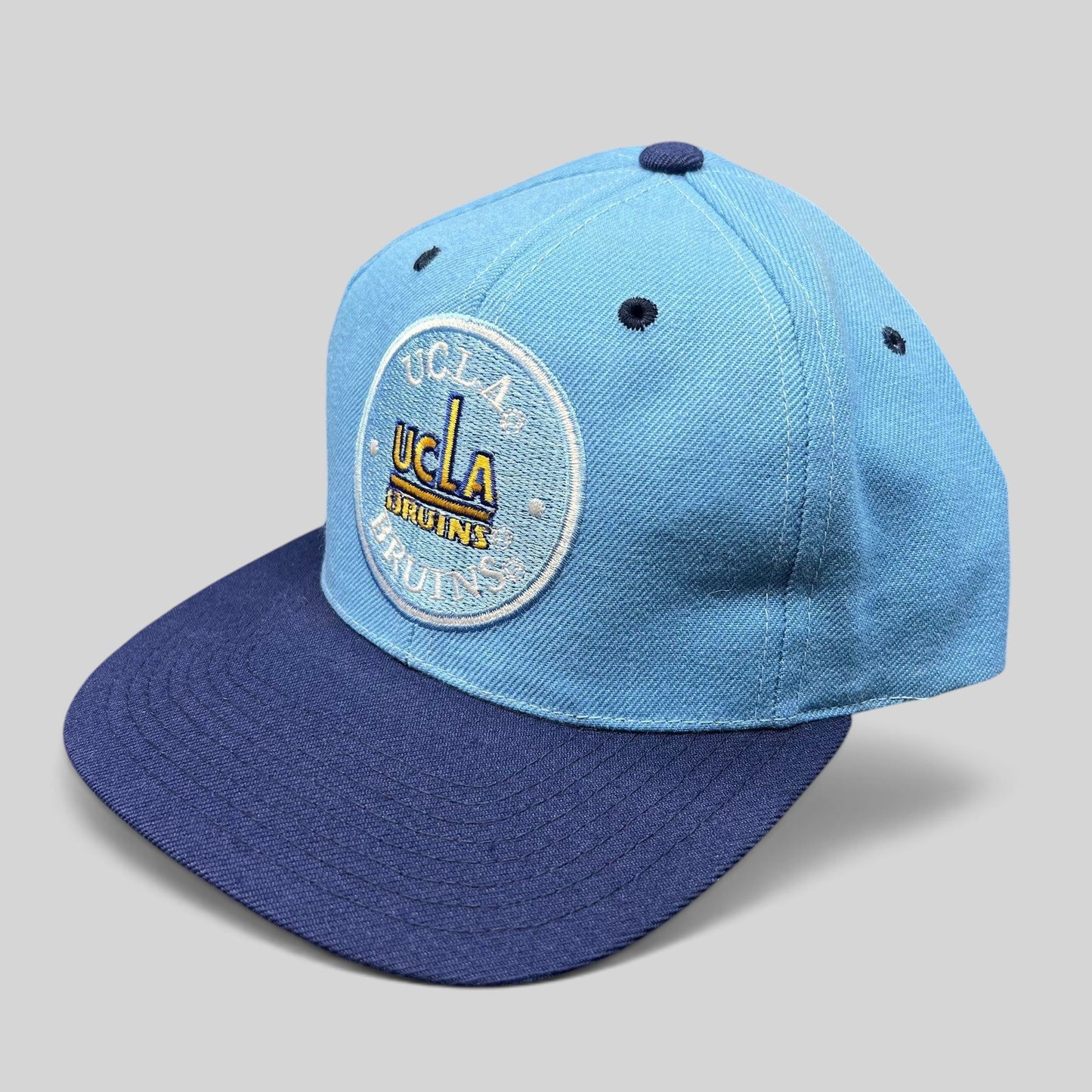 Raree Finds vintage 90s AJD UCLA Bruins snapback hat with light blue crown and navy brim featuring circular logo