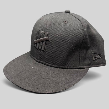 Raree Finds Undefeated 59FIFTY fitted hat in all black with tonal Five Strike logo embroidery and New Era side detail.