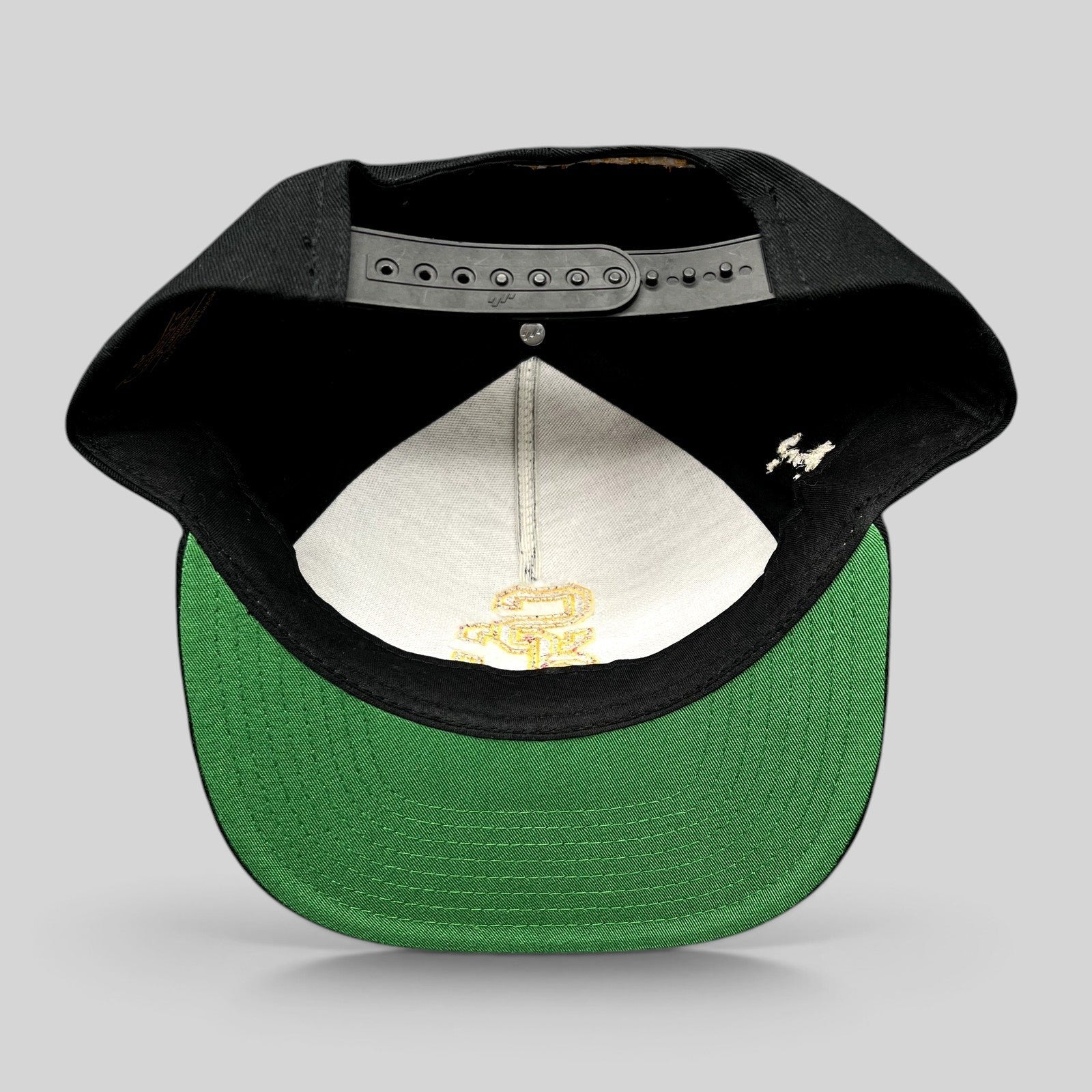Raree Finds USC Trojans snapback hat showing the interior black crown, green undervisor, and adjustable strap.