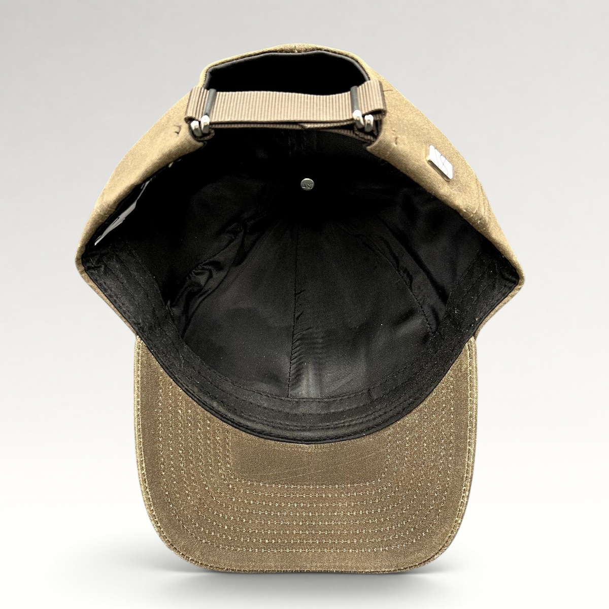 Raree Finds Varsity Headwear brown minimalist strapback cap showing the interior lining and adjustable nylon strap.