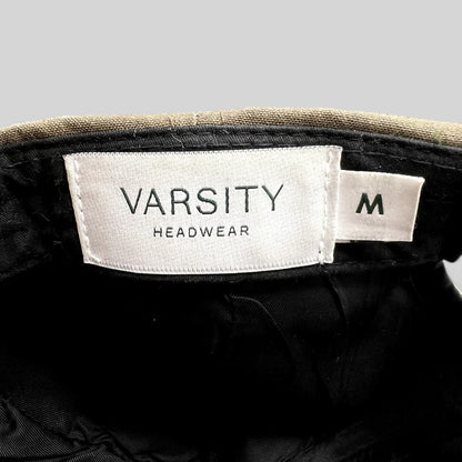 Raree Finds Varsity Headwear cap interior showing white brand label and size M tag against brown structured crown