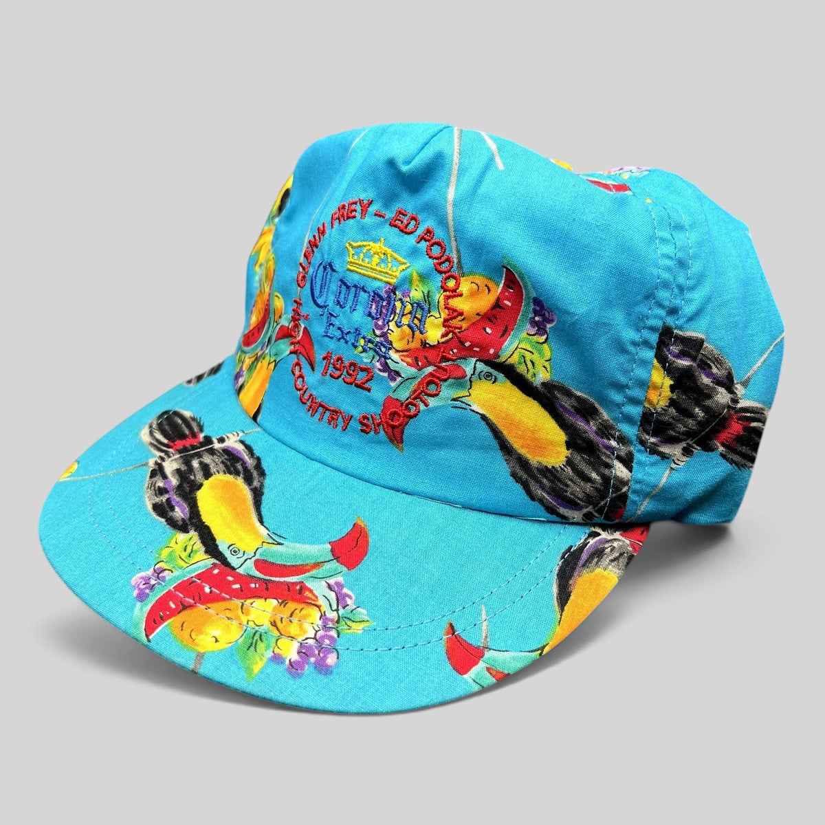 Raree Finds vintage 1992 High Country Shootout golf hat in turquoise with tropical toucan print and strapback closure.