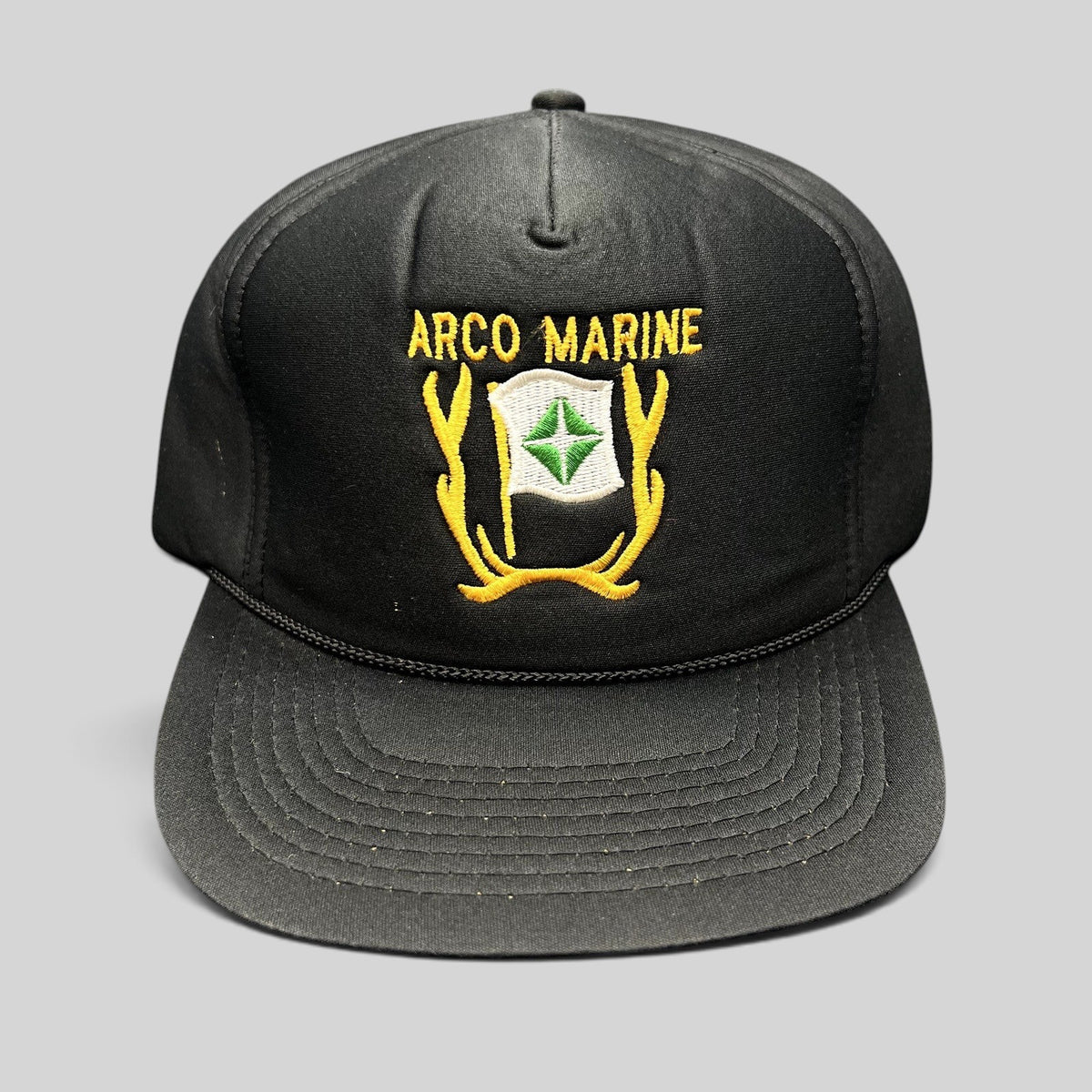Raree Finds vintage black ARCO Marine snapback hat with yellow and green embroidered logo and black rope brim detail.