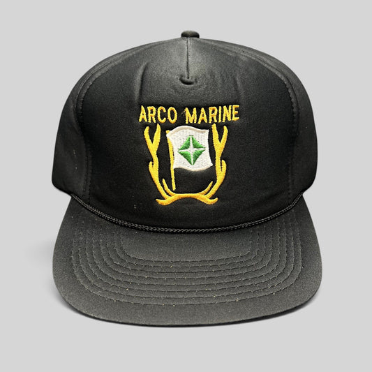 Raree Finds vintage black ARCO Marine snapback hat with yellow and green embroidered logo and black rope brim detail.