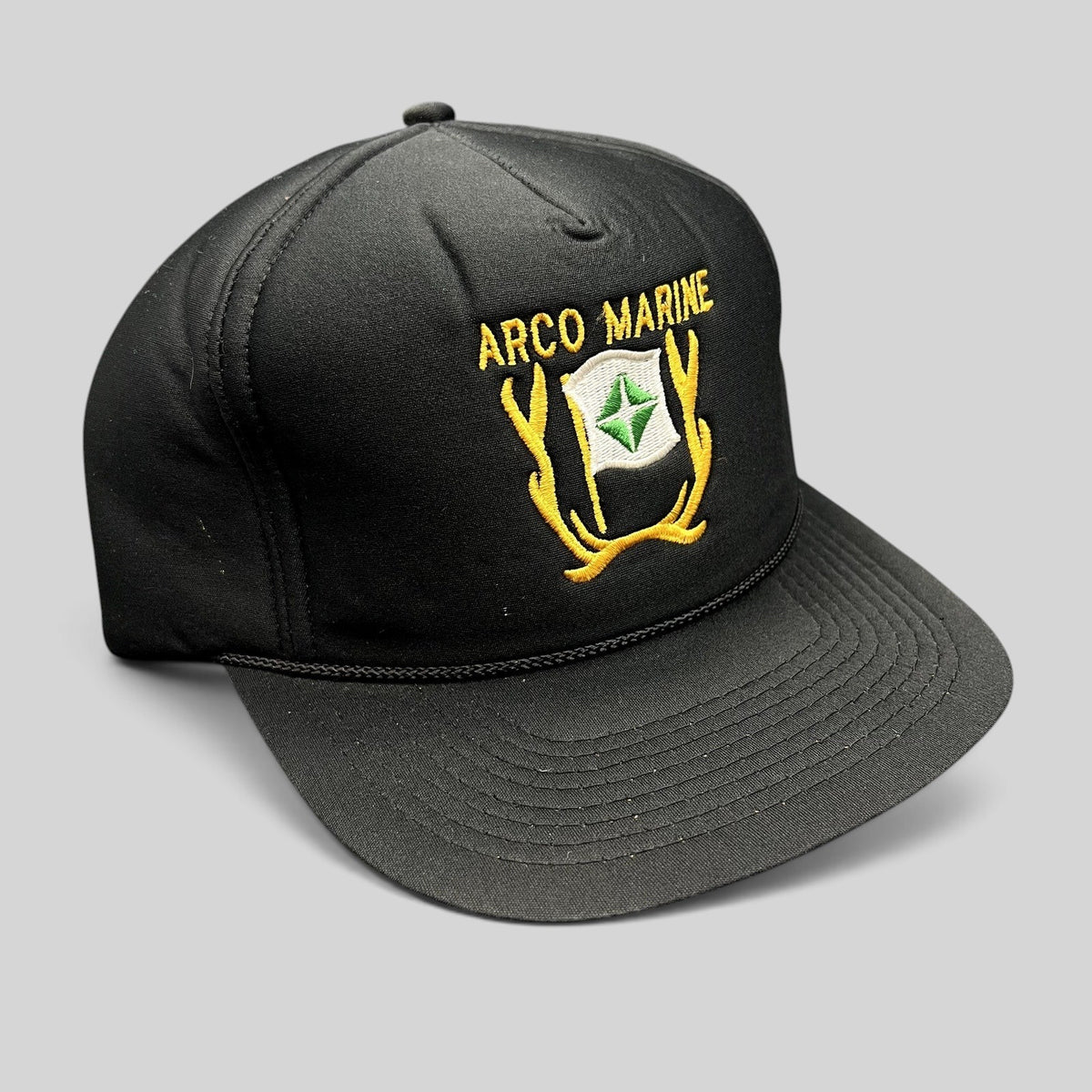 Raree Finds vintage black ARCO Marine snapback hat with yellow and green embroidered logo and black rope brim detail.