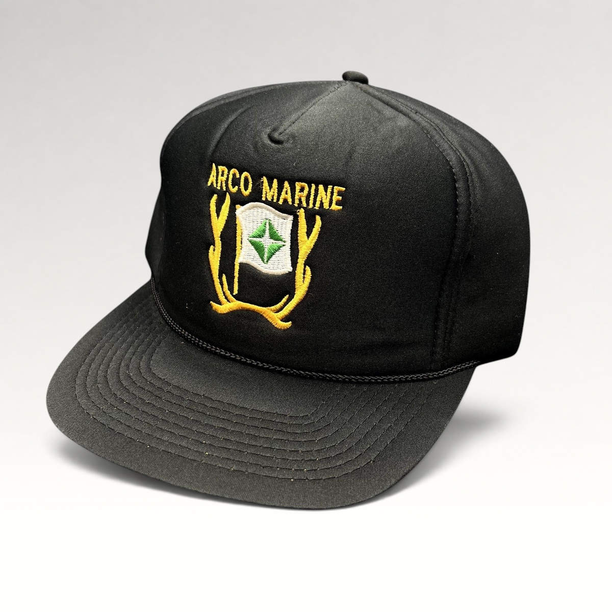 Raree Finds vintage black ARCO Marine snapback hat with yellow and green embroidered logo and black rope brim detail.