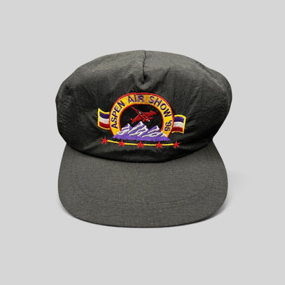Raree Finds vintage 1995 Aspen Air Show black nylon snapback hat with multicolor embroidered jet and mountain design.
