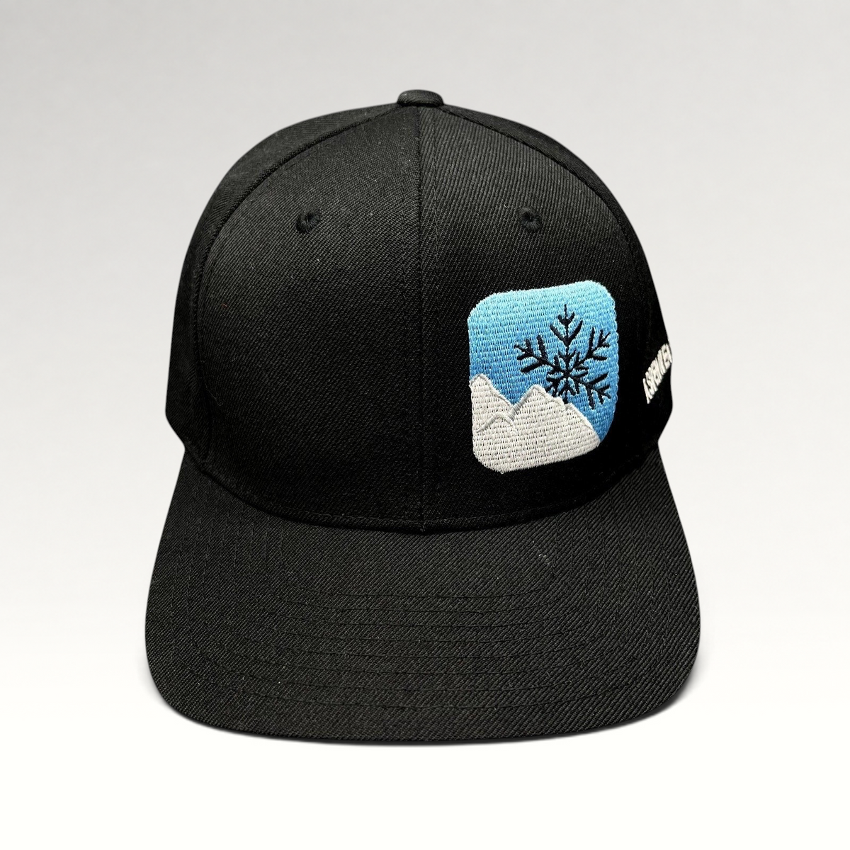 Raree Finds vintage black Yupoong snapback hat with embroidered mountain and snowflake logo and side text.