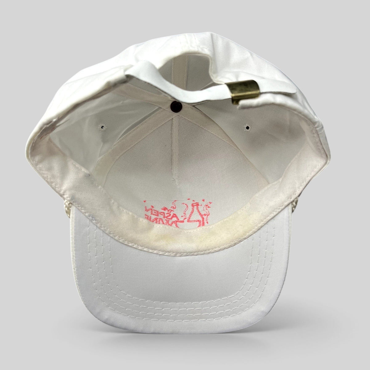 Raree Finds vintage 1991 Aspen Wine Party strapback hat in white with pink graphic and brass adjuster, interior view.