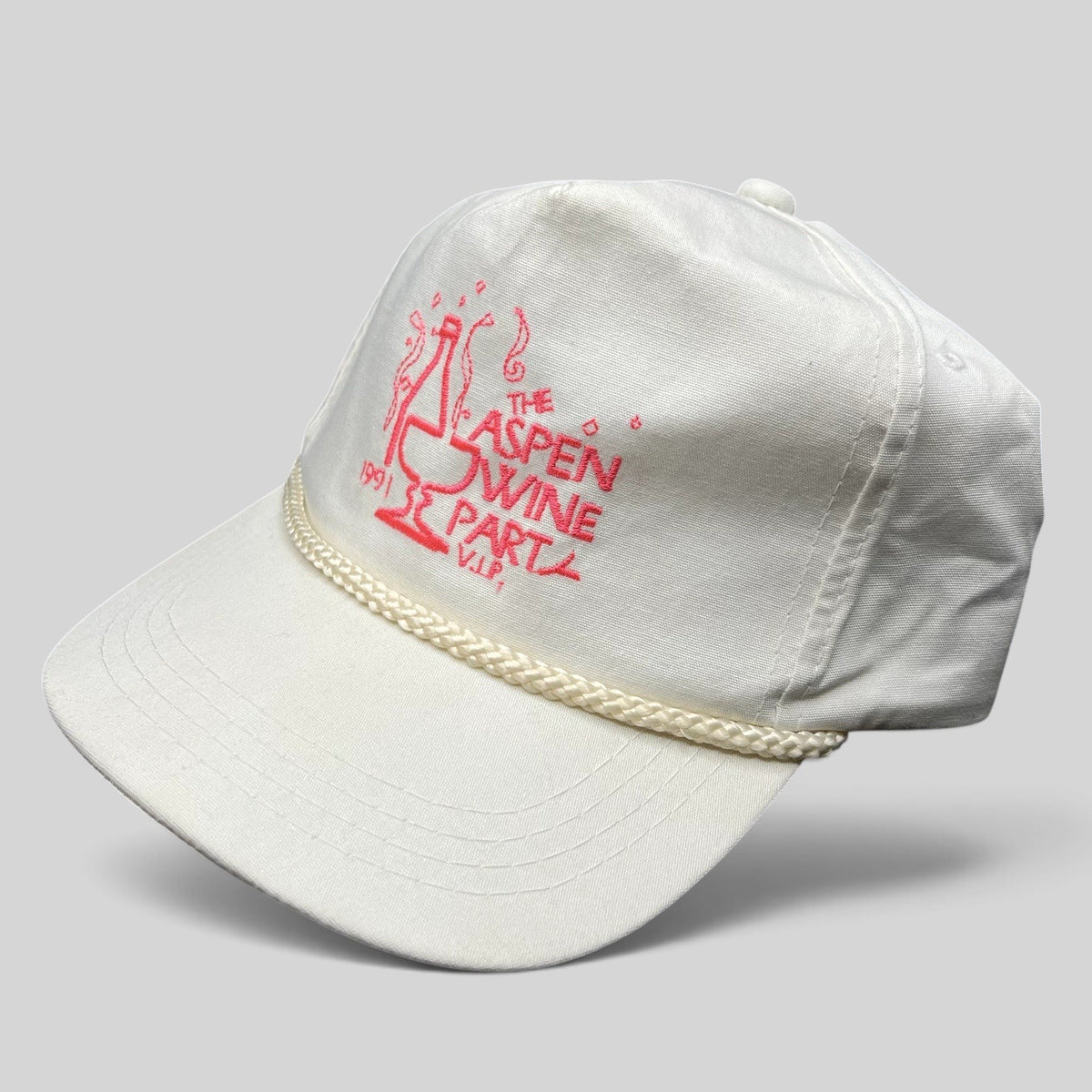 Raree Finds vintage 1991 Aspen Wine Party white strapback hat with pink graphic and decorative brim rope detail.