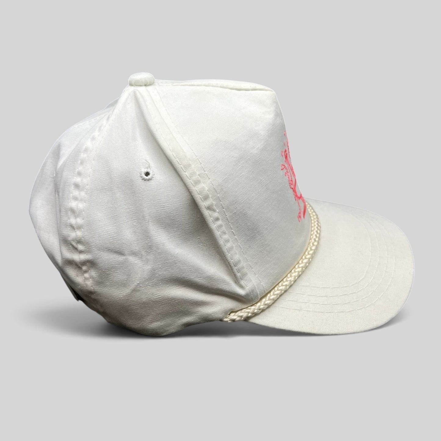 Raree Finds vintage 1991 white Yupoong strapback hat with pink champagne graphic and rope detail on the brim.
