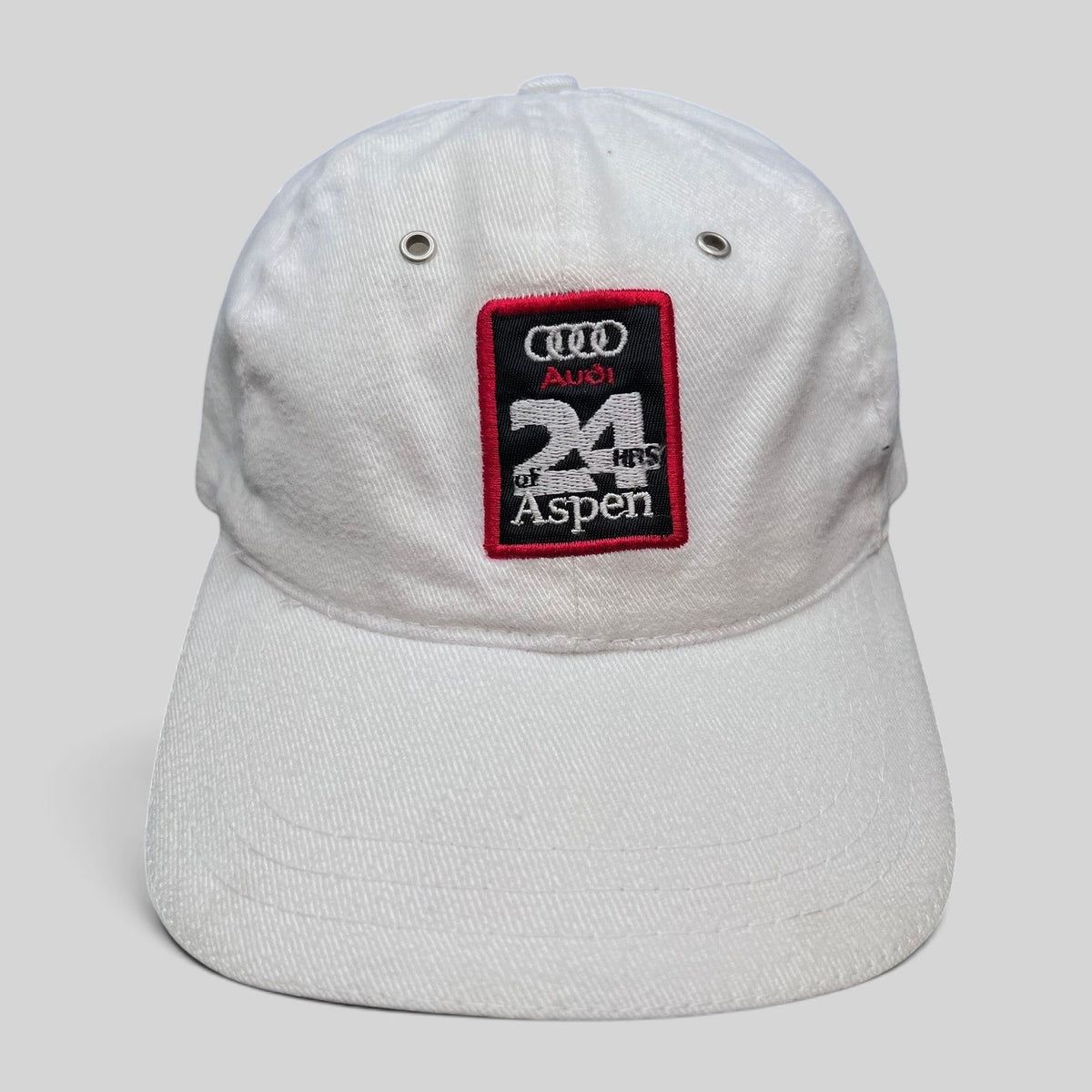 Raree Finds vintage white Audi 24 HRS of Aspen cotton strapback hat with a red and black embroidered racing patch.