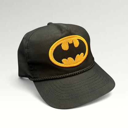 Raree Finds vintage black Batman snapback hat with a yellow embroidered bat logo and braided rope detail.
