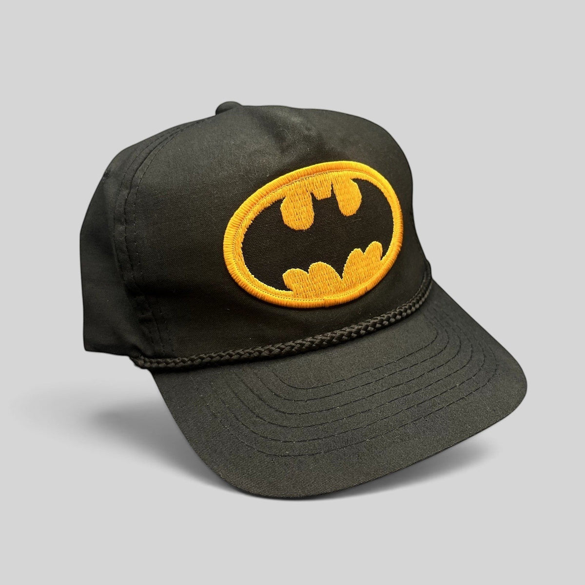 Raree Finds vintage black Batman snapback hat with a yellow embroidered logo patch and classic braided rope detail.