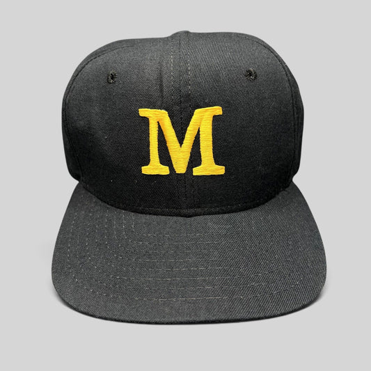 Raree Finds vintage New Era black snapback hat with a gold embroidered M logo on the structured front crown