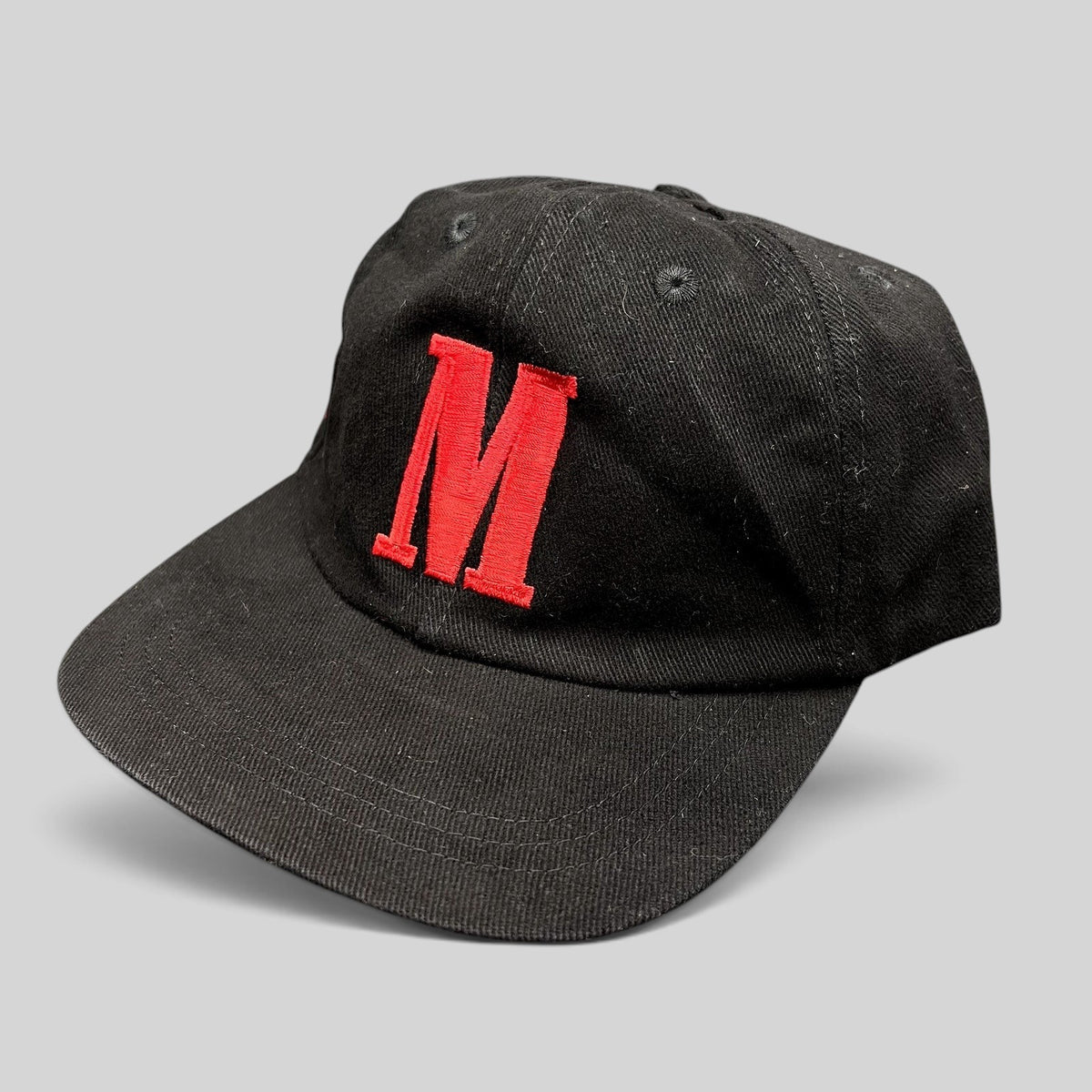 Raree Finds vintage black strapback hat with a red embroidered M logo on the front and a curved brim.