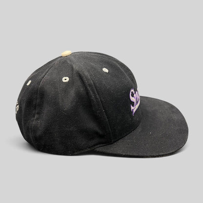 Raree Finds vintage 90s black snapback hat with purple script embroidery and a light gray brim, side profile view.