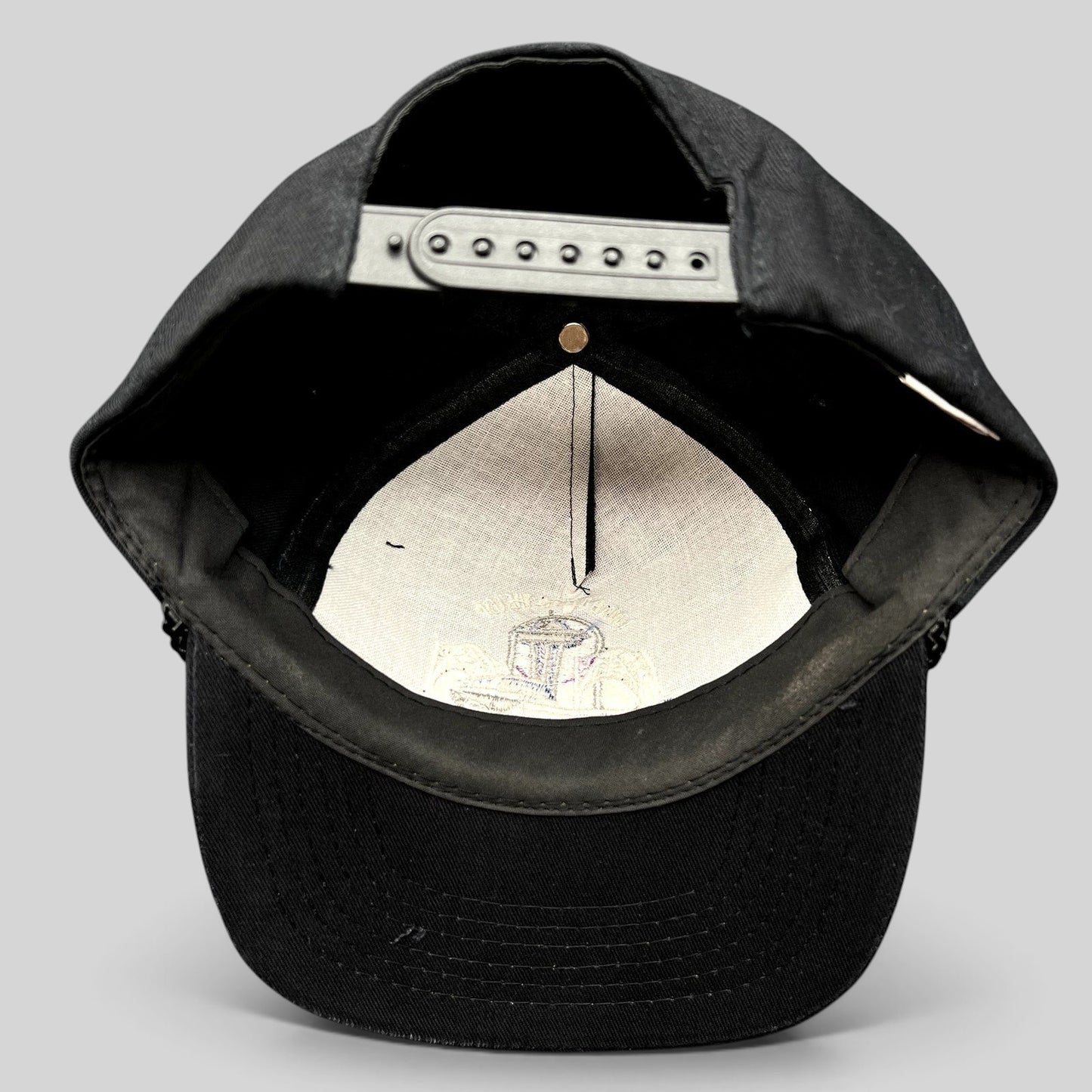 Raree Finds vintage 90s black snapback hat interior showing adjustable plastic strap and embroidered crown lining