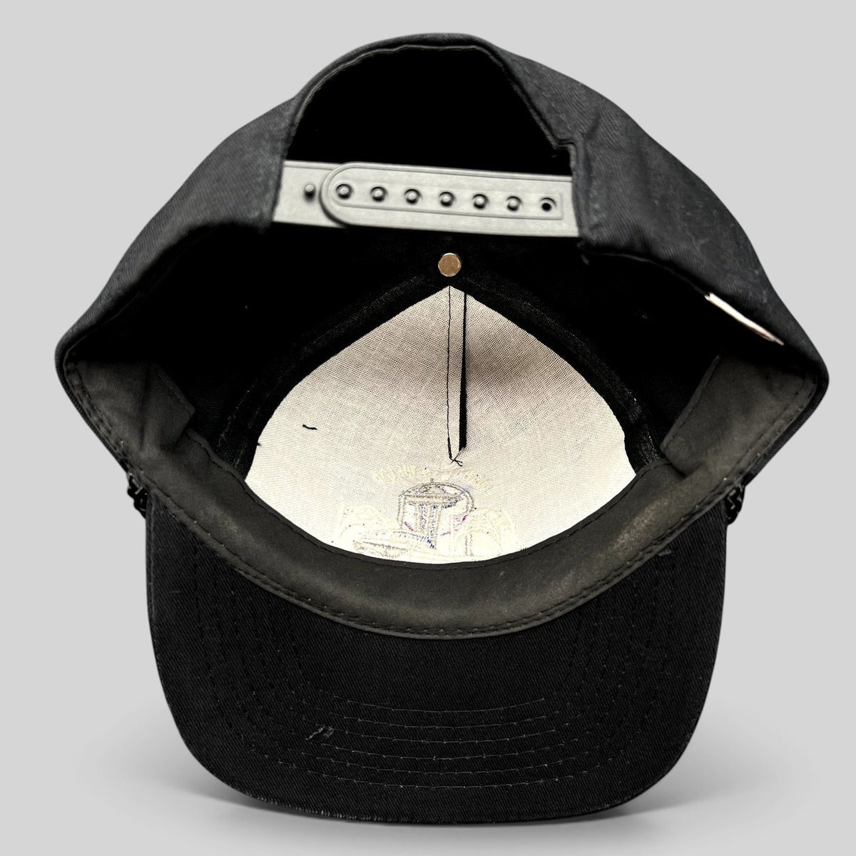 Raree Finds vintage 90s black snapback hat interior showing adjustable plastic strap and embroidered crown lining