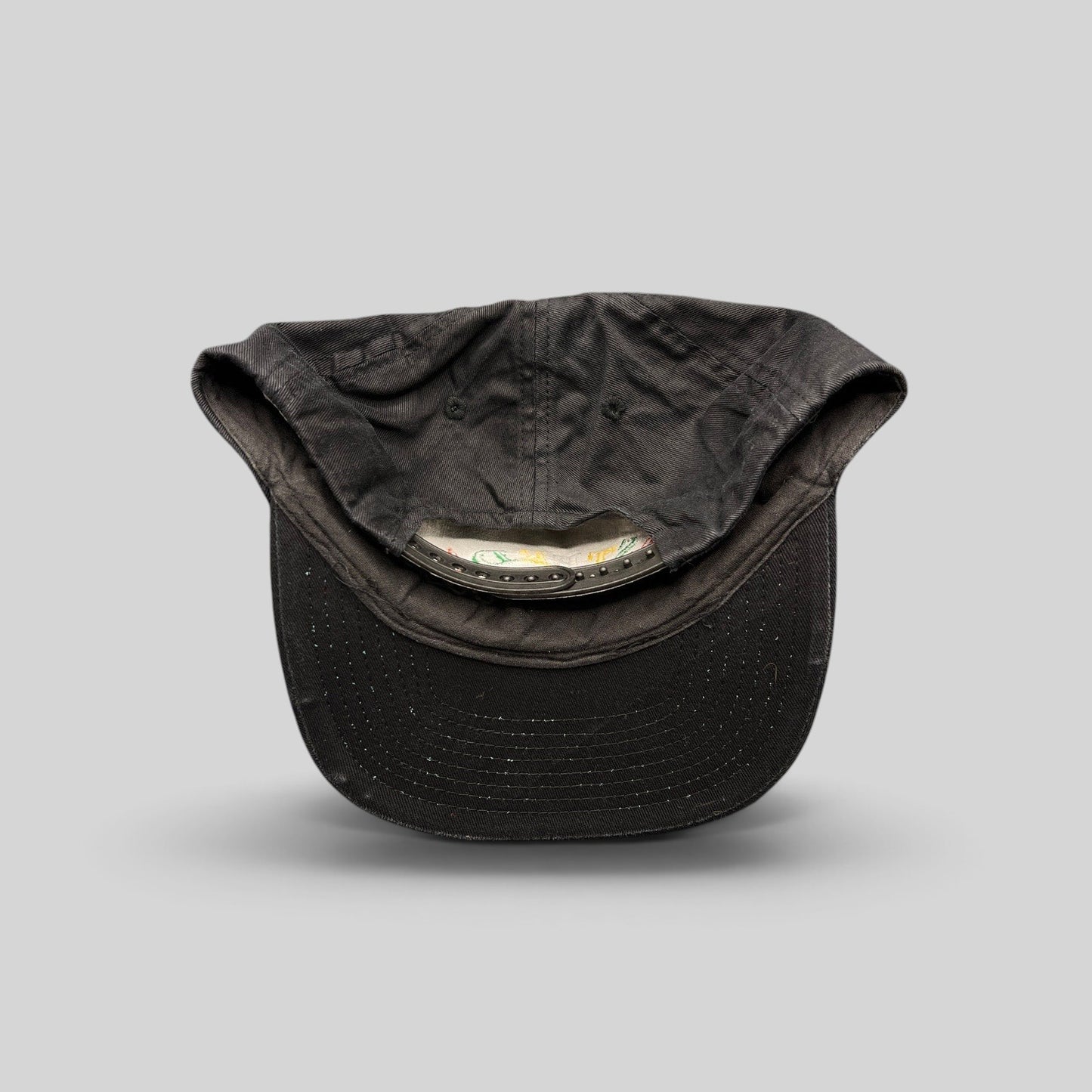 Raree Finds vintage 1990s black cotton snapback hat showing the interior adjustable plastic strap and unstructured crown
