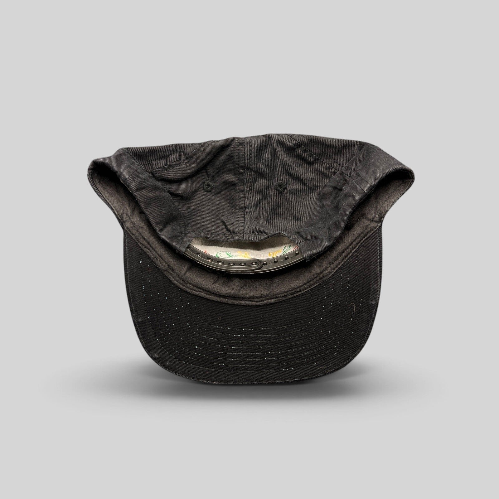 Raree Finds vintage 1990s black cotton snapback hat showing the interior adjustable plastic strap and unstructured crown