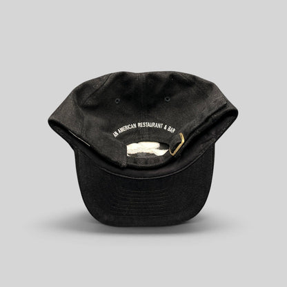 Raree Finds vintage black cotton strapback hat with white embroidered text on the back and brass-tone buckle closure.