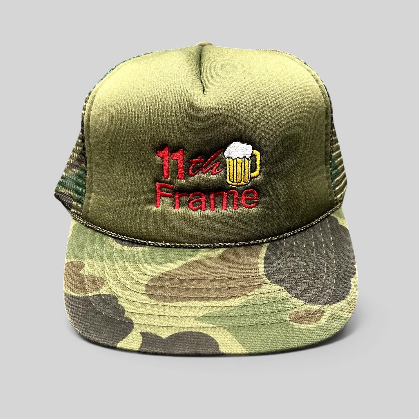 Raree Finds vintage 11th Frame bowling trucker hat with olive foam front, woodland camo brim, and beer mug embroidery.