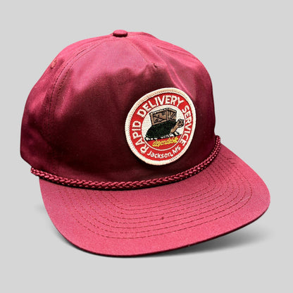 Raree Finds vintage burgundy trucker hat with a Rapid Delivery Service embroidered patch and braided rope brim detail.